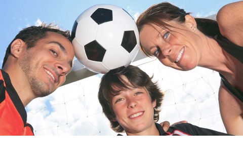 Positive soccer parents and their son holding a soccer ball with their heads